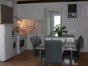 Enjoy meals in this kitchen with appliances, a stove, and microwave, adjacent to a dining area with a table for two.