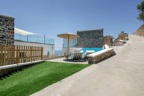 A pool area with lounge chairs, a table, and a pergola.