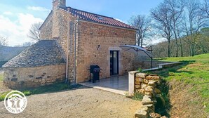 A stone building with a red-tiled roof, a door, and a grill outside. - Domaine de Ratier - LES Arques (LES ARQUES)