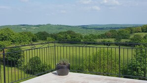 Uma varanda com vista para uma paisagem verde.