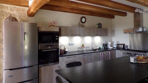 Cozinha moderna com eletrodomésticos de aço inoxidável, vigas de madeira e uma ilha central.