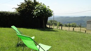 Una silla plegable verde en un área cubierta de césped, con vistas a colinas al fondo.