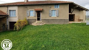 Una casa de dos pisos con techo de tejas, un pequeño porche y un césped bien cuidado.