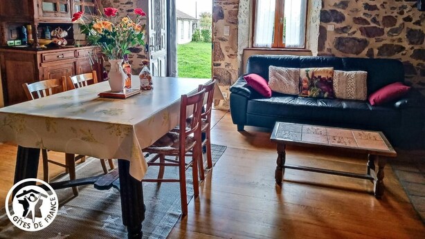 Un interior rústico con pared de piedra, muebles de madera, una mesa de comedor y un sofá.