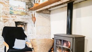Una habitación acogedora con pared de piedra, una silla de madera, un tablero de ajedrez y un estufa de leña.