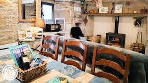 Una habitación rústica con paredes de piedra, una chimenea y un comedor con sillas y una mesa de madera.
