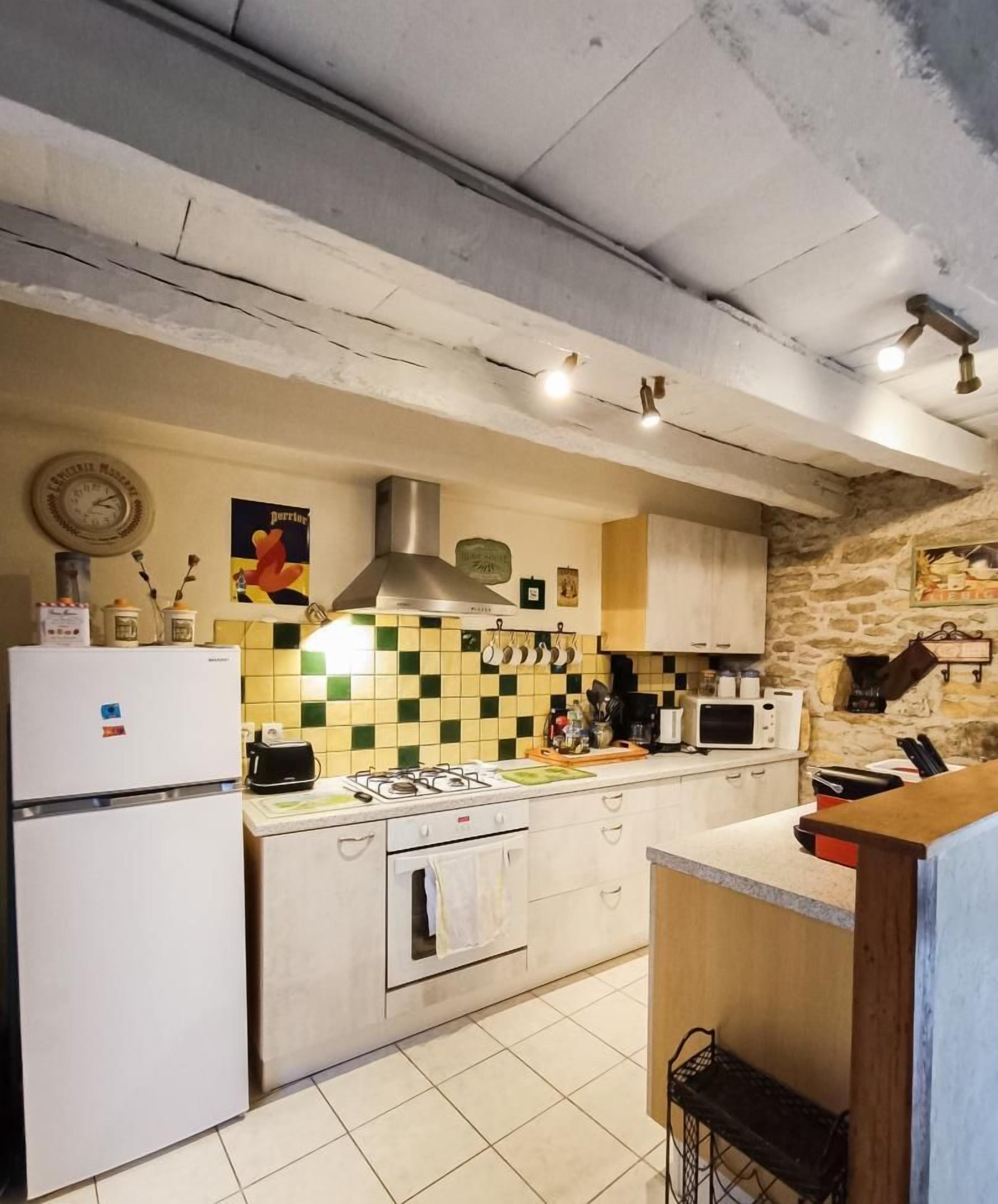 Una cucina con rivestimento in piastrelle, un fornello, un frigorifero e un lavandino.