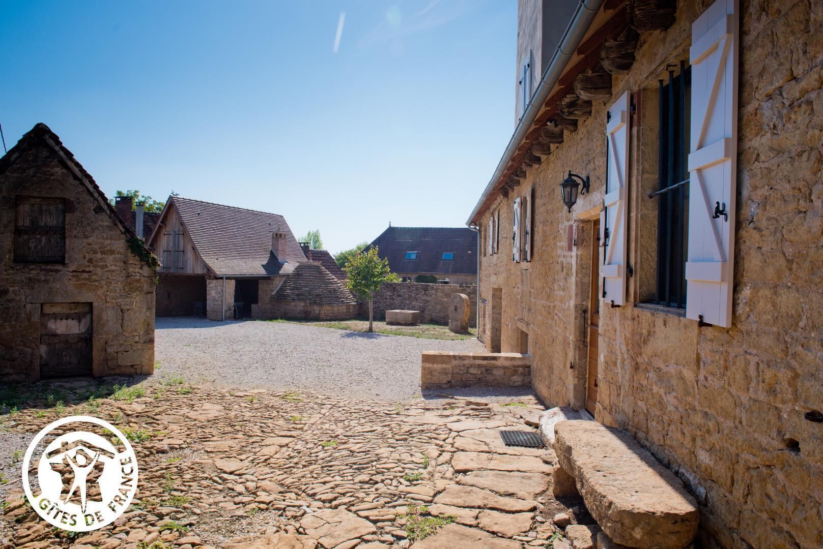 Een landelijk stenen gebouw met een kinderafdeling van geplaveid steen, met traditionele architectuur en een heldere hemel.