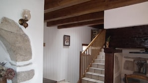 A staircase with wooden railings and a tiled floor, leading to a room with white walls and a stone accent wall.