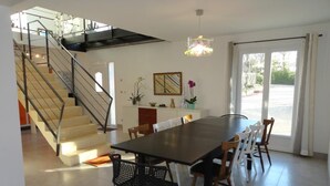 Un'area pranzo moderna con un tavolo grande, sedie e una scala che conduce a un piano superiore.