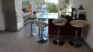 Una cucina moderna con isola centrale, due sgabelli da bar, un frigorifero e un forno a microonde.