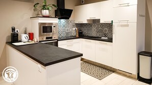 Una cocina moderna con armarios blancos, una encimera negra, un microondas, una cafetera y una planta en maceta.