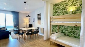 A modern room with a bunk bed, a dining area with a table and chairs, a TV, and a large window with curtains. - The Cliffs A Ribeira - Rapadoira (Foz)