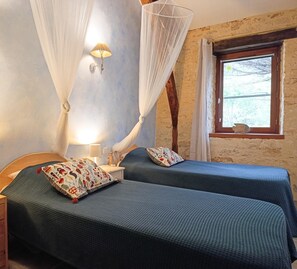 Un dormitorio con dos camas, una ventana con vistas y una mesita de noche con lámpara.