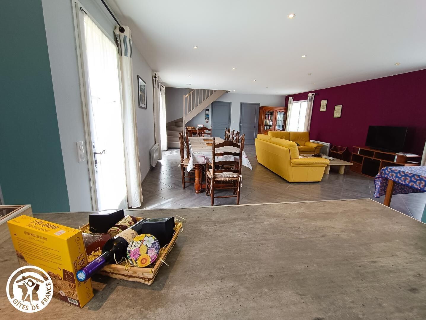 A spacious living area with a dining table, yellow sofa, and a TV.