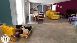 A spacious living area with a dining table, yellow sofa, and a TV.