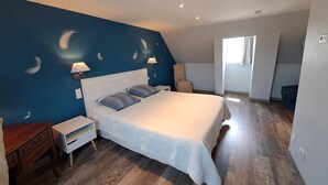 A bedroom with a large bed, two bedside tables, a chair, and a window.
