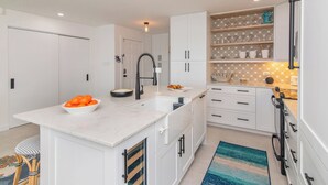 Een moderne keuken met witte kasten, een marmeren aanrecht en een inbouwspoelbak.