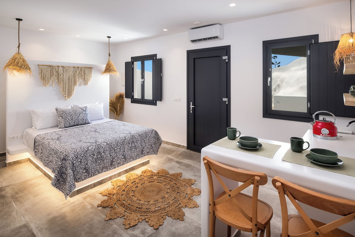 A modern bedroom with a bed, bedside tables, and a dining area with chairs and a table.
