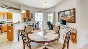 A dining area with a round table, chairs, and a kitchen in the background. - Port Charlotte Home ~ 3 Mi to Beach & Harbor! (Port Charlotte)