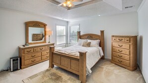 Ein Schlafzimmer mit einem Holzbett, einem Schminktisch, einem Spiegel und einem Deckenventilator.