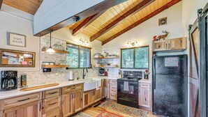 A kitchen with wooden cabinets, a black refrigerator, and a red rug. - Breathtaking Lake Views Walk to Alpine Lake (Terra Alta)