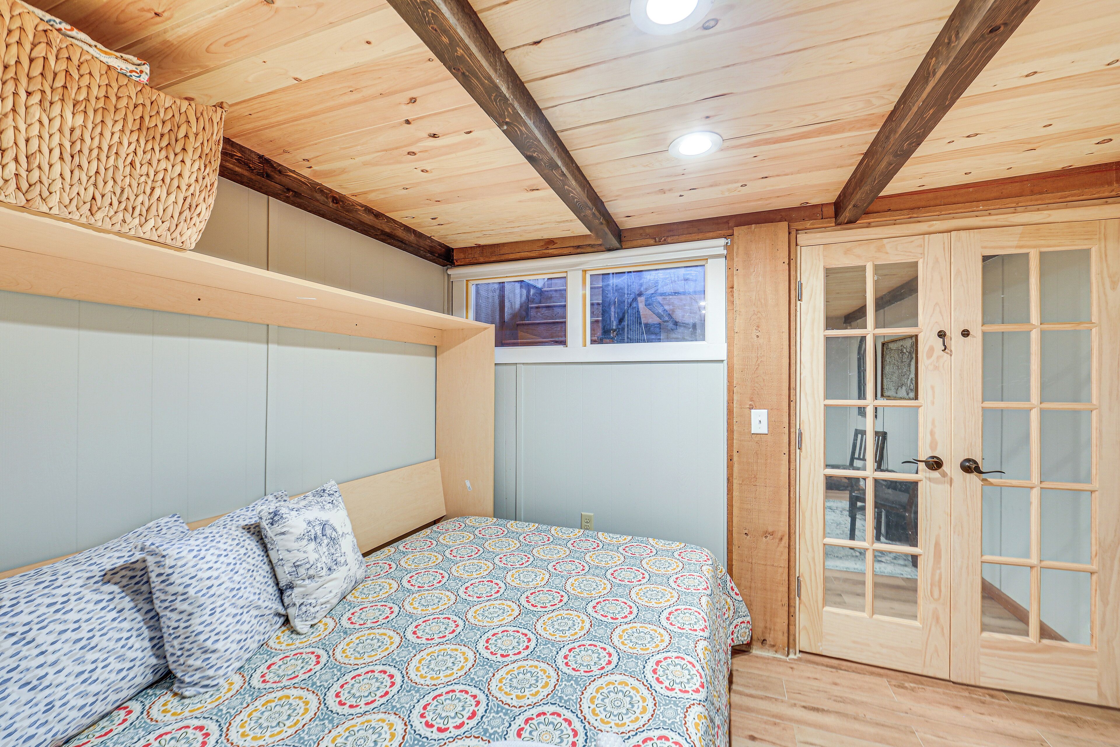 Ein Zimmer mit einem Bett, Holzboden und einer Tür mit Glasfeldern.