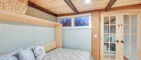 Ein Zimmer mit einem Bett, Holzboden und einer Tür mit Glasfeldern.