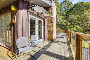 A wooden deck with outdoor seating, a stone wall, and a view of trees. - Breathtaking Lake Views Walk to Alpine Lake (Terra Alta)