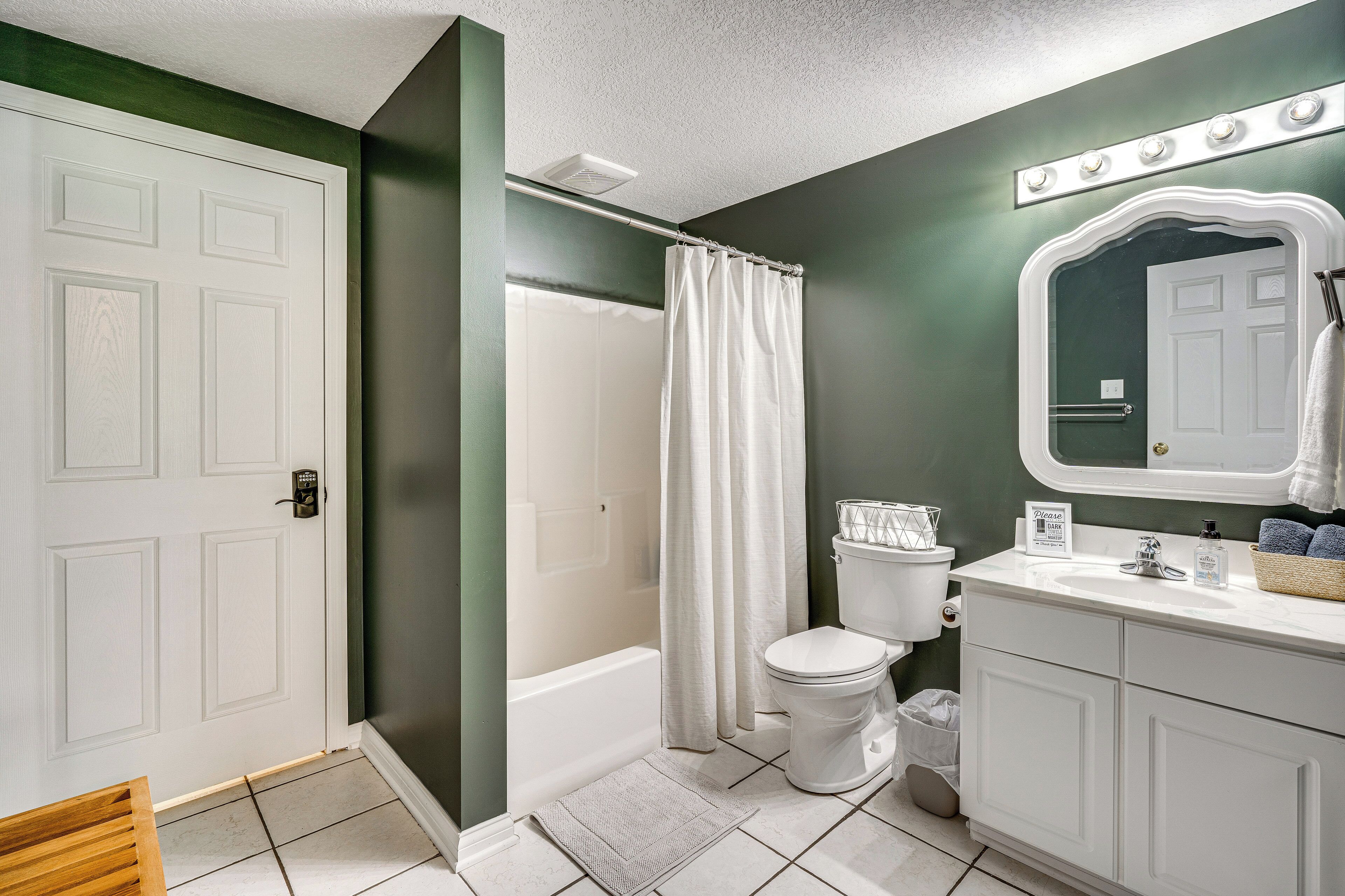 A bathroom with a shower, toilet, sink, and vanity.