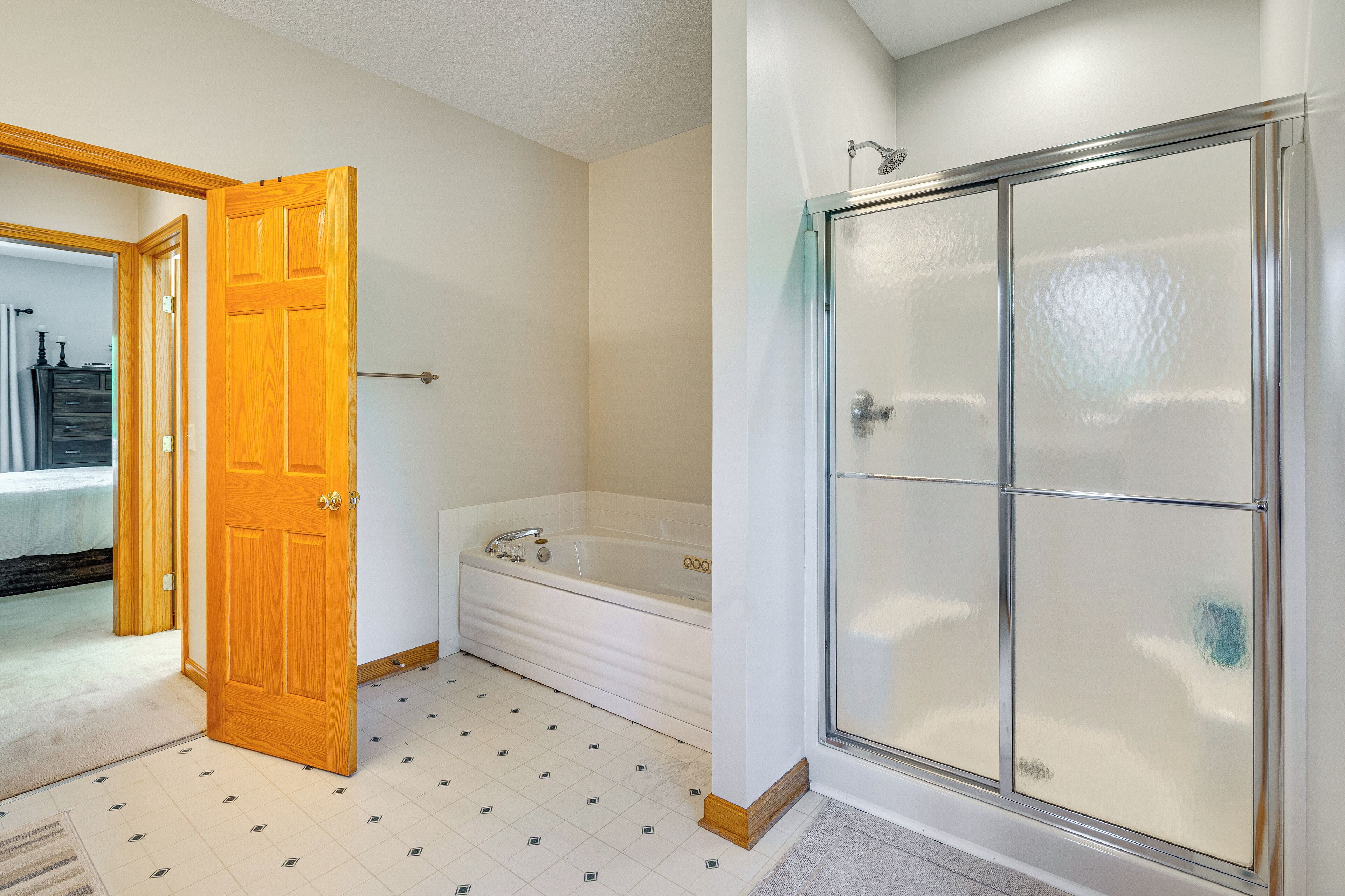 Un baño con bañera, cabina de ducha y puerta de madera.