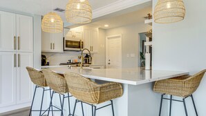 A modern kitchen with white cabinetry, a central island with bar stools, and hanging wicker pendant lights. - Private Fishing Dock: Waterfront Palmetto Home! (Palmetto)