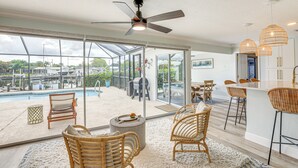 A spacious indoor area with a ceiling fan, wicker furniture, a bar area, and a view of a pool and outdoor patio. - Private Fishing Dock: Waterfront Palmetto Home! (Palmetto)