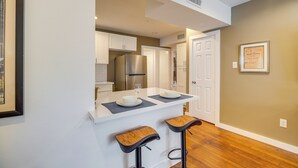 A kitchen with white cabinets, a stainless steel refrigerator, and a white countertop. There are two bar stools with wooden seats. - 1 Mi to Dtwn, 8 Mi to Nrg! Fourth Ward Apt w/ W&D (Houston)