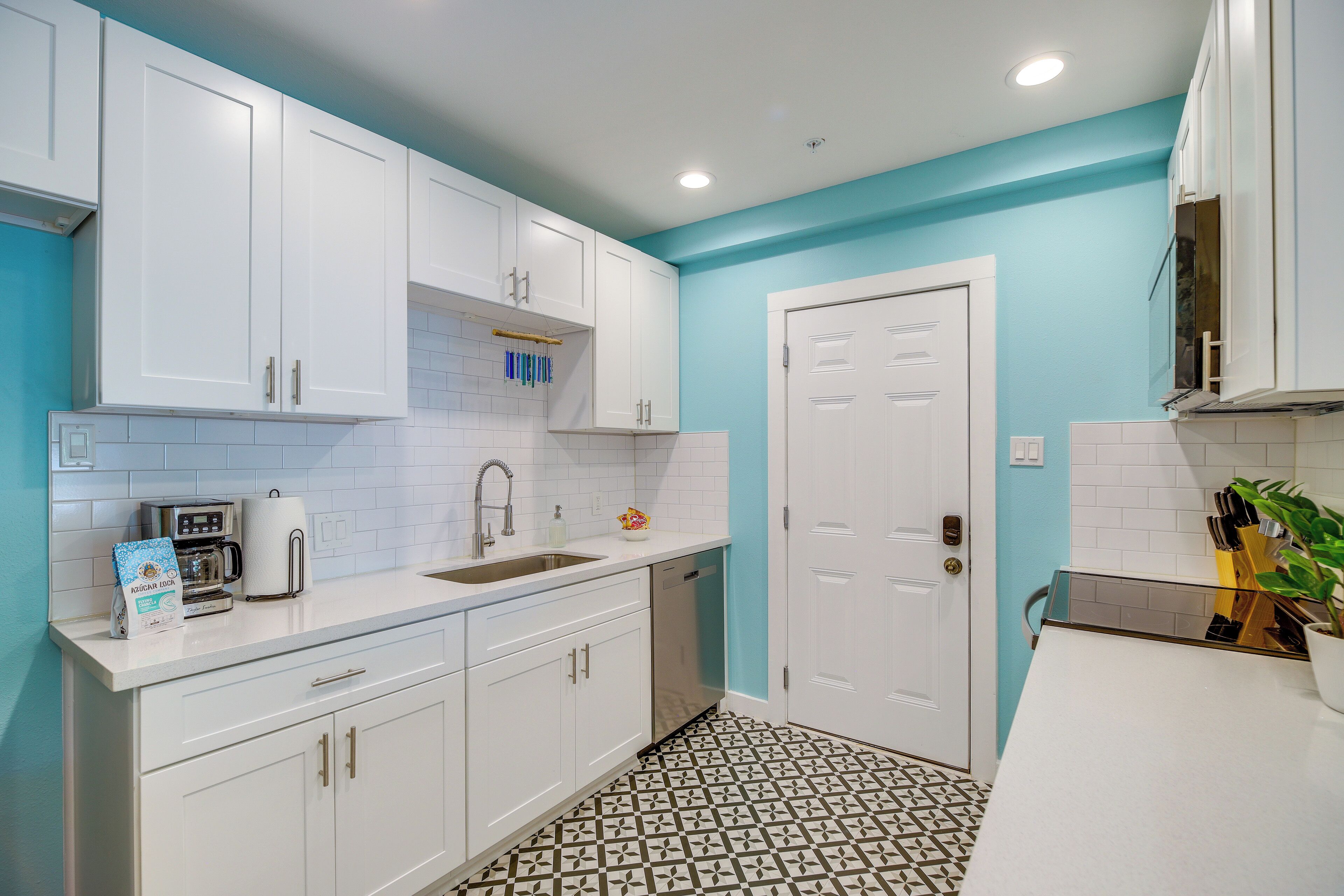 A kitchen with white cabinets, a sink, a coffee maker, and a dishwasher.