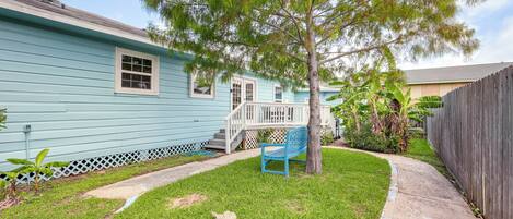 A light blue house with a white porch and a blue bench.