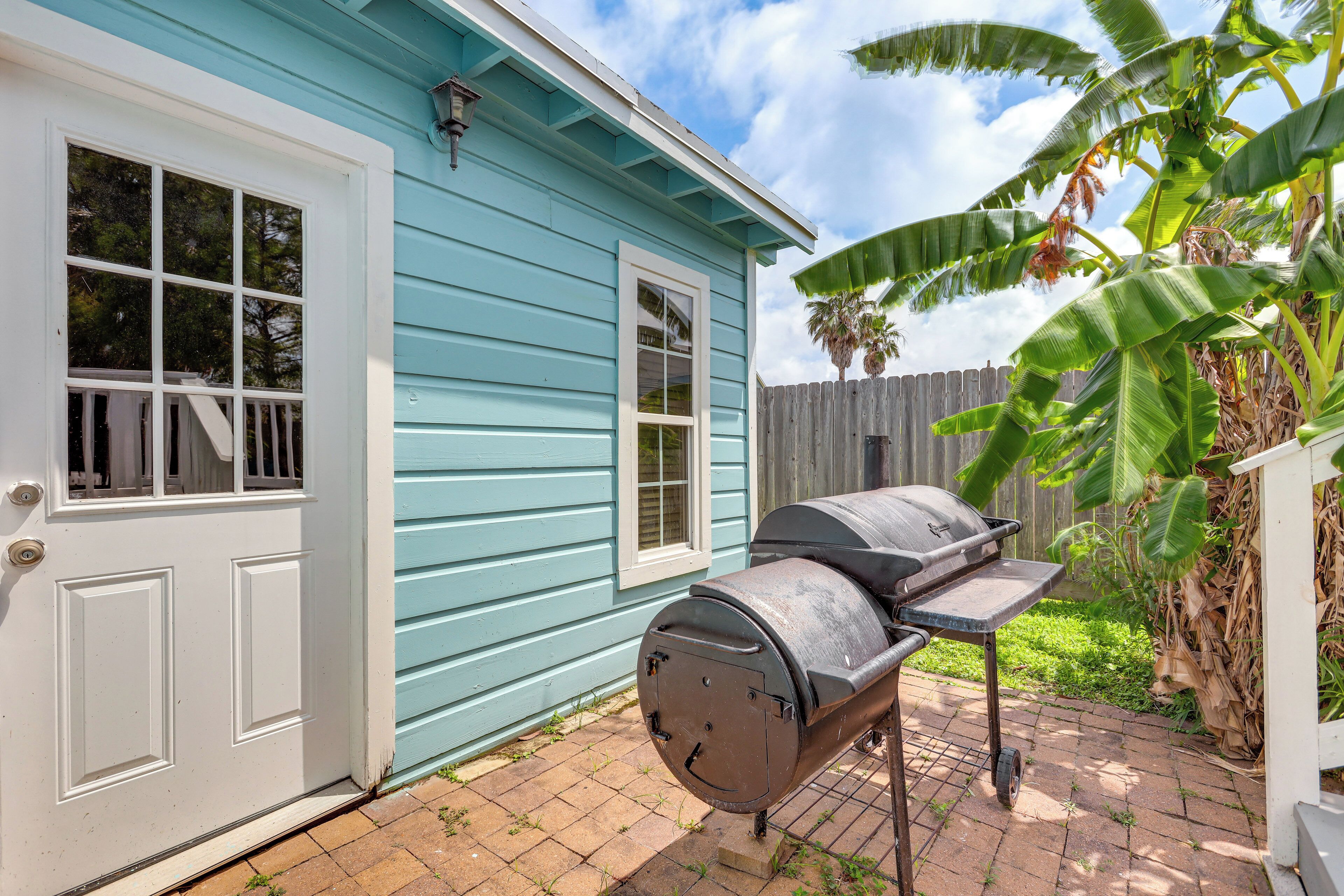 Una casa con facciata blu, una porta bianca e un barbecue nel giardino.