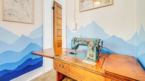 A vintage sewing machine on a wooden table in a room with mountain-themed walls and a map. - Manitou Mountain Retreat: Deck & Fire Pit! (Manitou Springs)