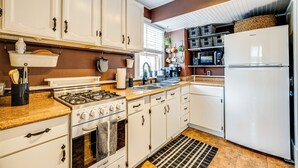 A kitchen with white cabinets, a gas stove, a refrigerator, and a microwave. - Manitou Mountain Retreat: Deck & Fire Pit! (Manitou Springs)