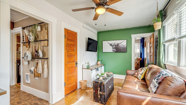 A living room with a brown leather sofa, a ceiling fan, and a green wall. - Manitou Mountain Retreat: Deck & Fire Pit! (Manitou Springs)