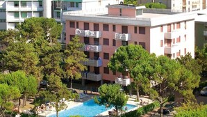 Un hôtel doté d’une piscine entourée d’arbres, offrant une vue sur la mer et comprenant plusieurs balcons équipés de climatiseurs.