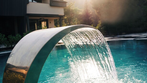 A modern building with a swimming pool and a waterfall feature. - Minta Hills Villas Kemer (Kemer)