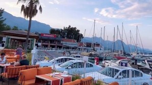 A marina with boats docked, outdoor seating with orange cushions, and a McDonald's restaurant in the background. - Minta Hills Villas Kemer (Kemer)