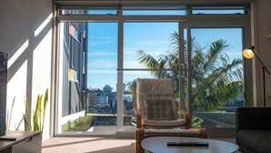 Un salon moderne doté d’une grande porte-fenêtre coulissante, d’un fauteuil confortable, d’une petite table ronde et d’un canapé.