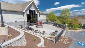 A building with a patio area featuring outdoor seating and a stone wall. - Resort Amenities, Mountain Views, Sauna! (McGaheysville)