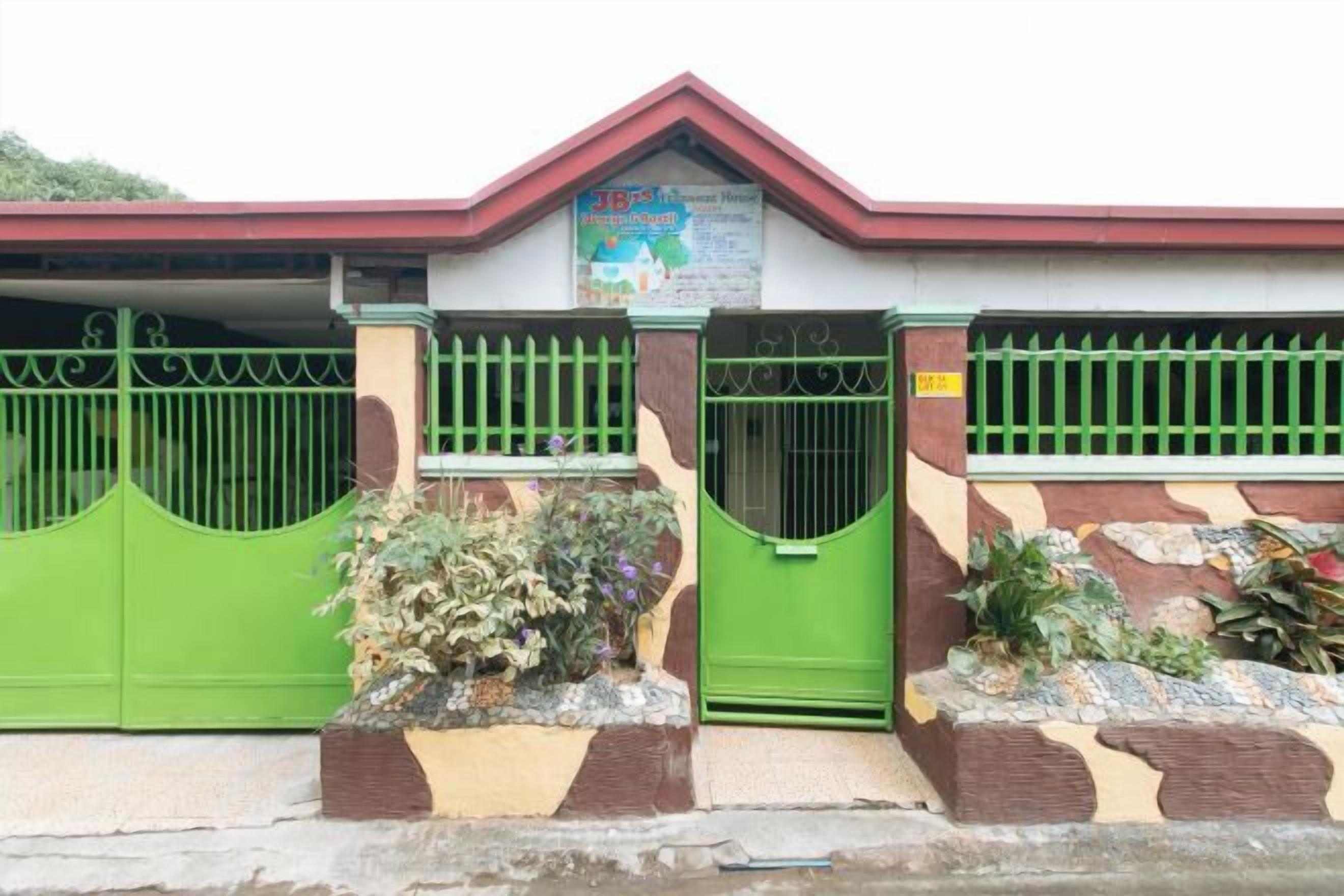 A building with a gated entrance, a red roof, and a sign above the gate.