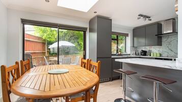 A modern kitchen with a marble countertop, a built-in oven, and a large window overlooking a garden.