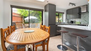 A modern kitchen with a marble countertop, a built-in oven, and a large window overlooking a garden. - Charming Retreat Near Grange Hill (Central Line) (Greater London)