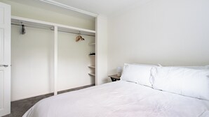 Une chambre à coucher avec un lit, une armoire et une table de chevet avec une lampe.