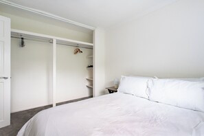 Une chambre à coucher avec un lit, une armoire et une table de chevet avec une lampe.